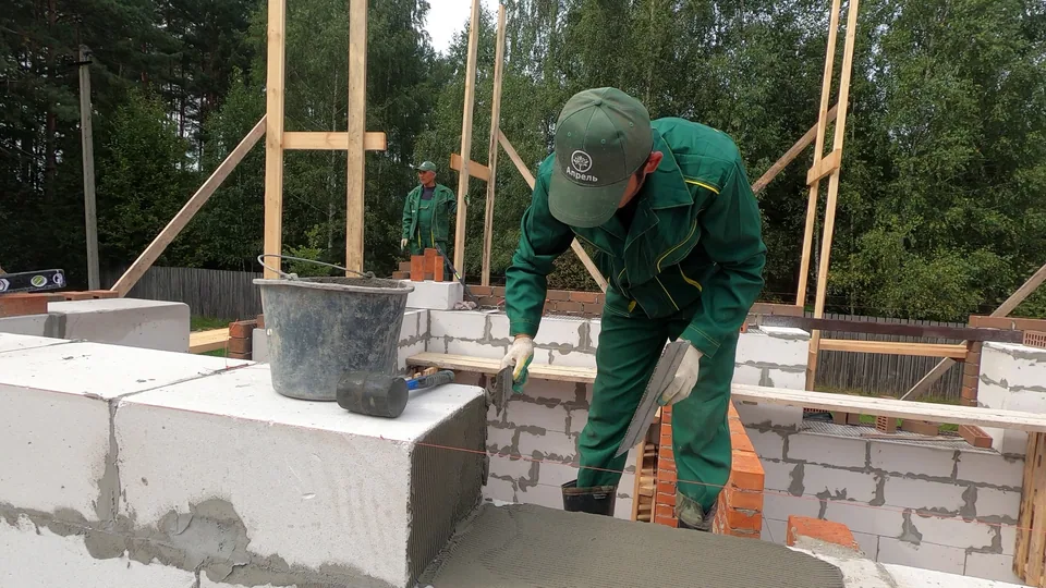 Каменщик укладывает очередной ряд блоков