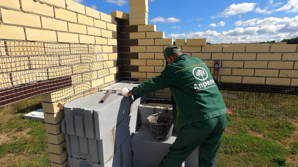 Каменщик устанавливает блок у кирпичной облицовки