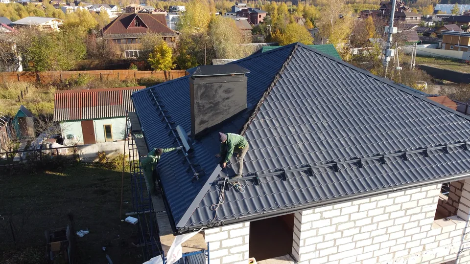 Рабочие на четырёхскатной крыше дома из блоков