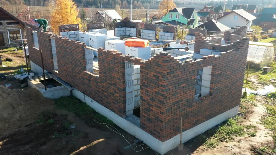 Кирпичные стены дома с формирующимися оконными проёмами