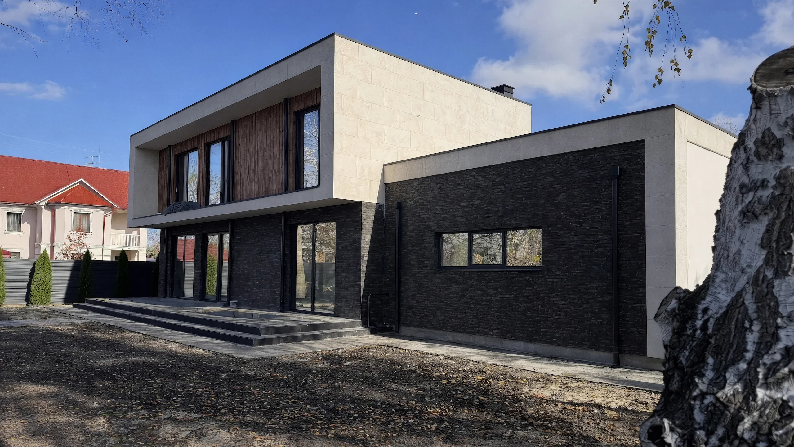 Уличный фасад двухэтажного дома 429 м² с черным гаражным объемом, белым вторым этажом и деревянной вставкой