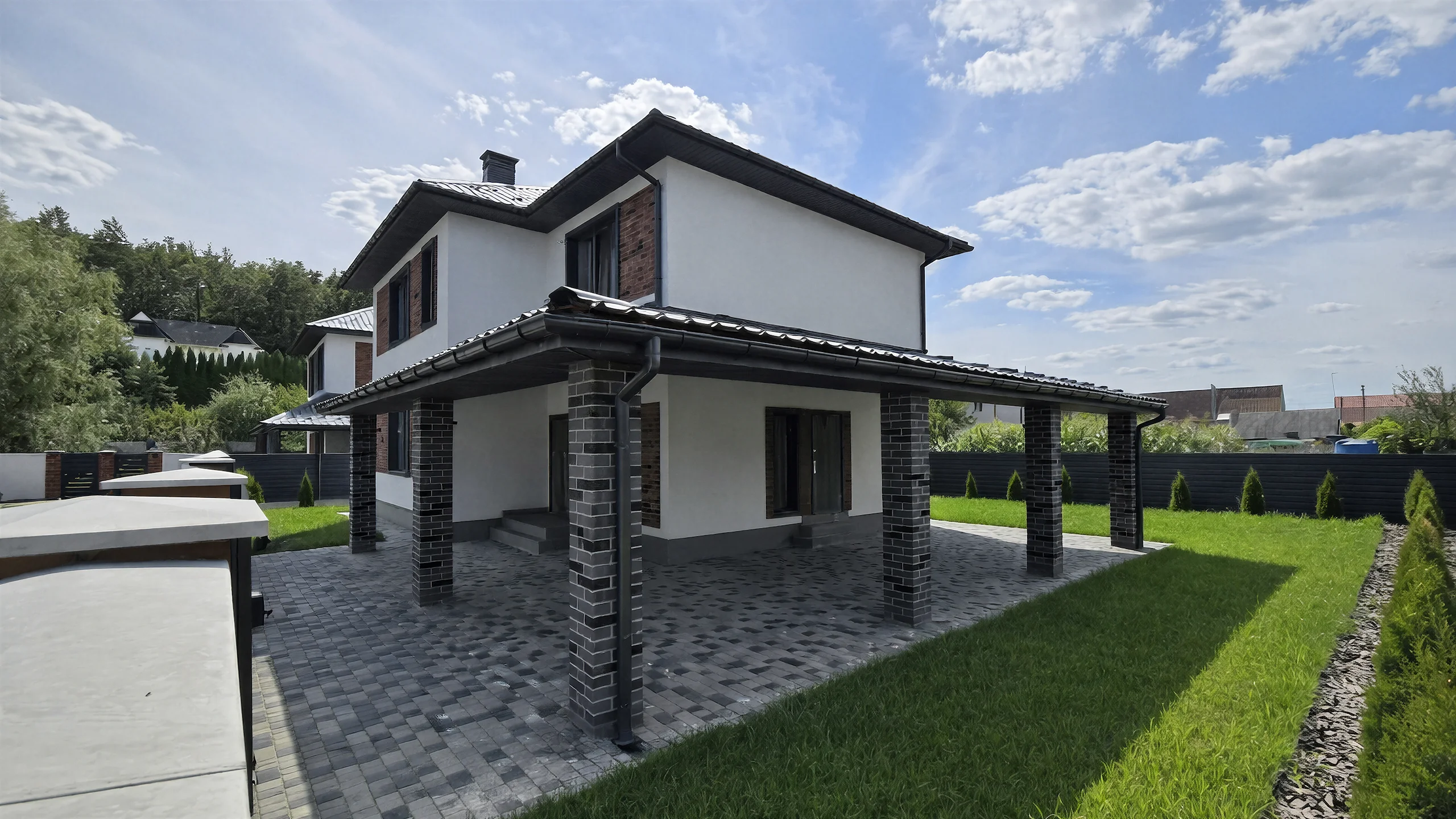 Дворовый ракурс двухэтажного дома 250 м² с газоном, террасой, темной кровлей и белой отделкой