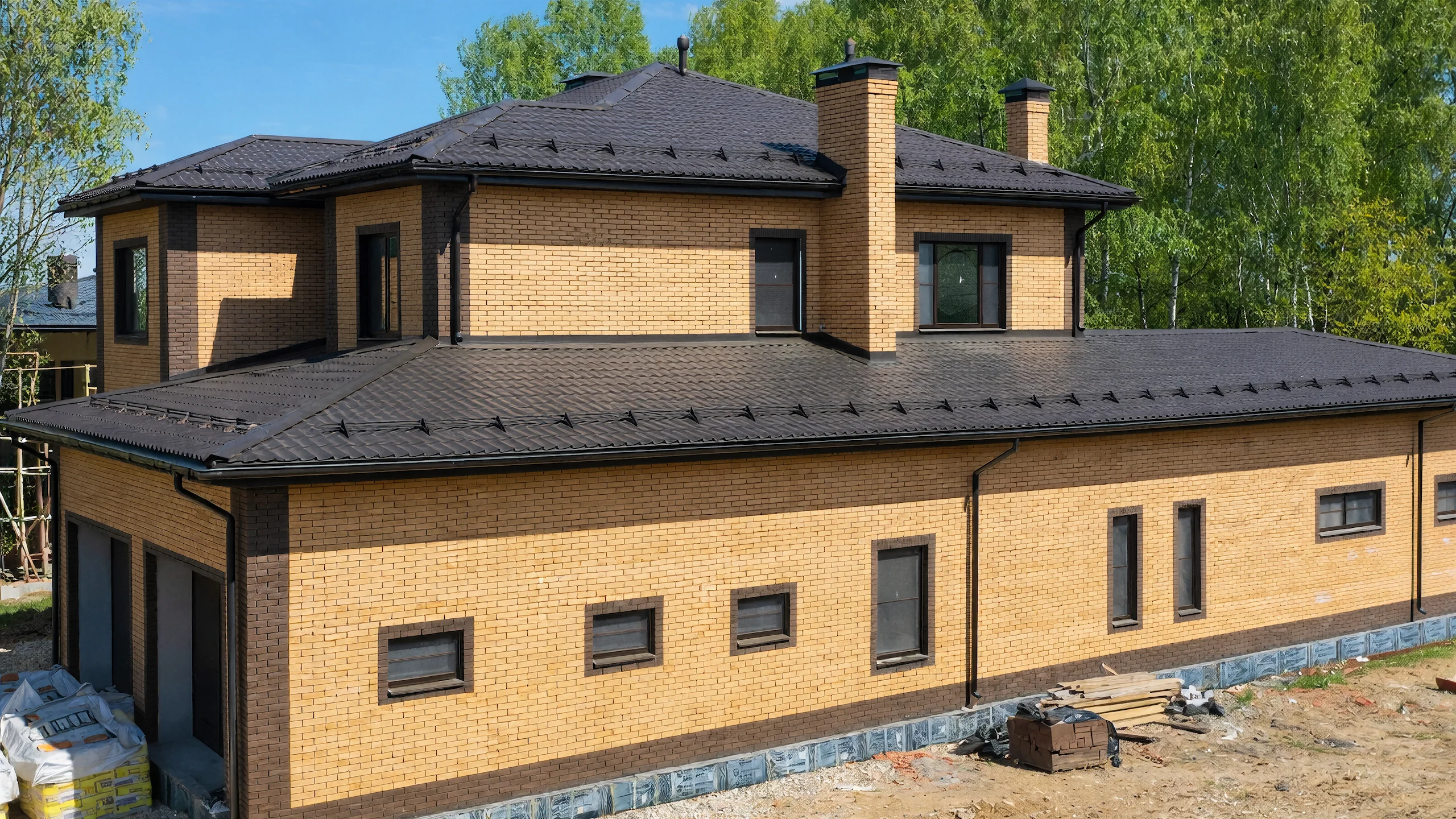 Длинный боковой фасад двухэтажного дома 382 м² с одноэтажным крылом, кирпичом и узкими окнами