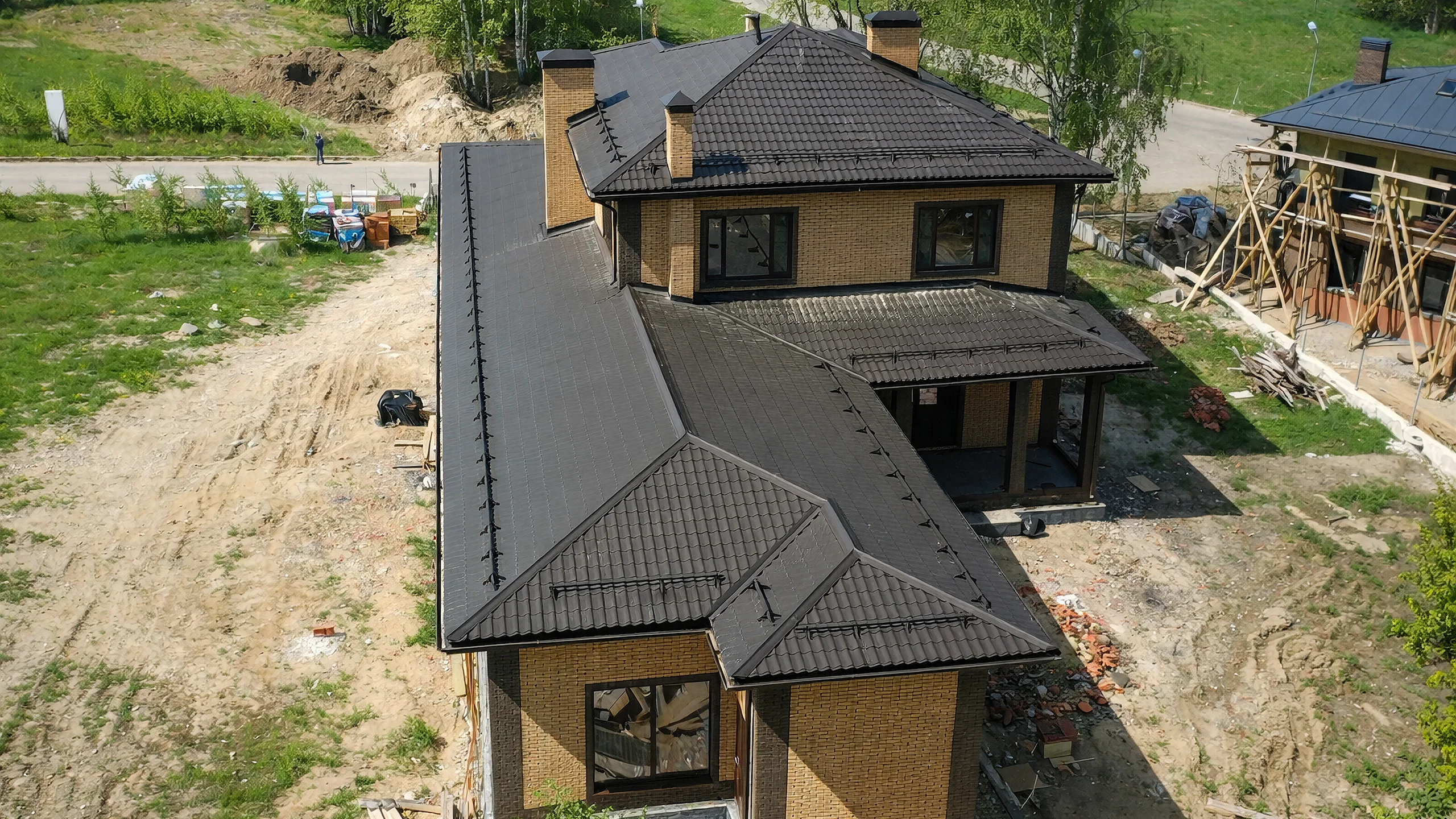 Вид сверху на дом 382 м² с двором, темной кровлей и крытым въездом в гараж
