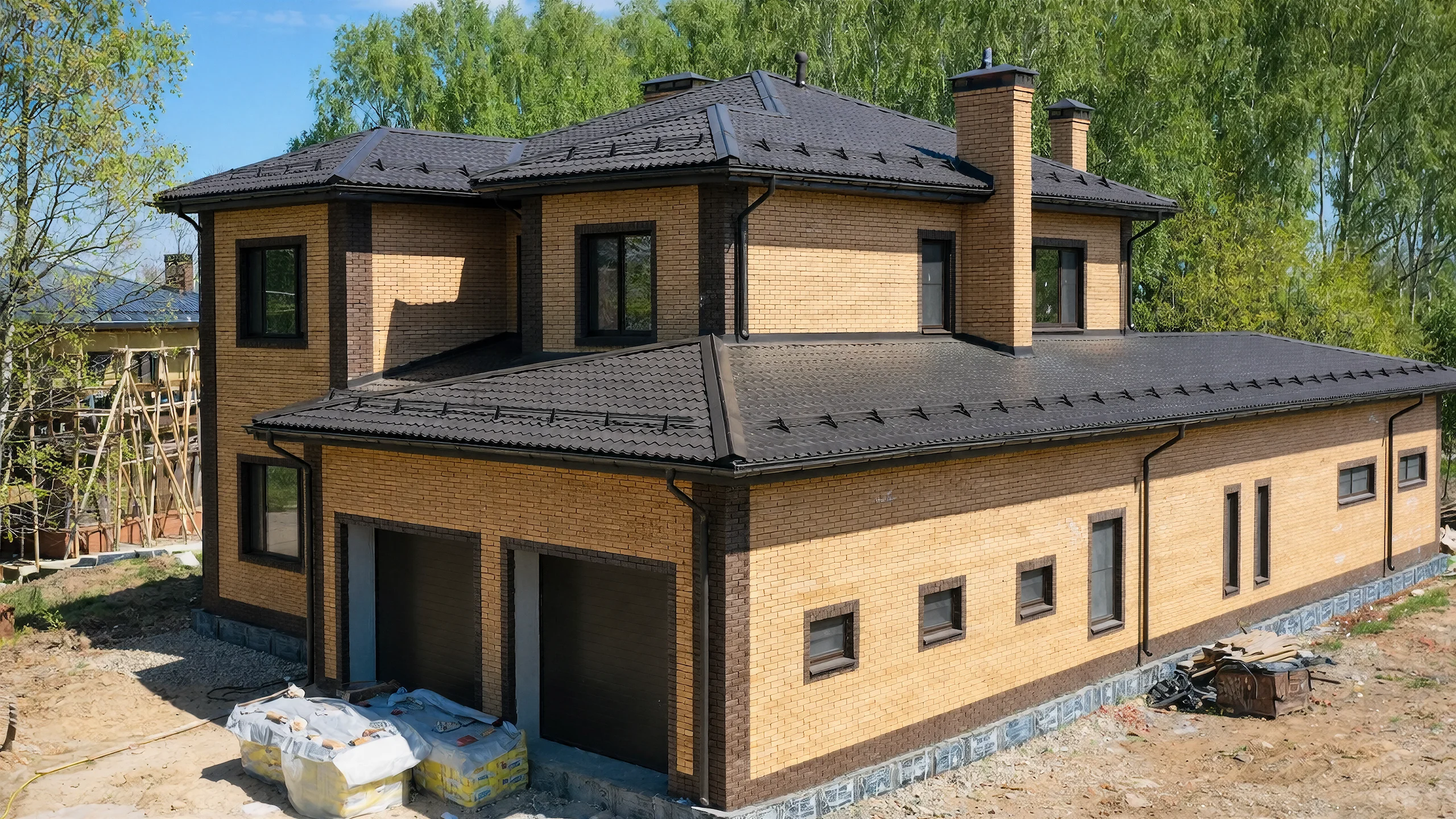 Угловой ракурс двухэтажного дома 382 м² с кирпичной отделкой, дымоходами и темной черепичной кровлей