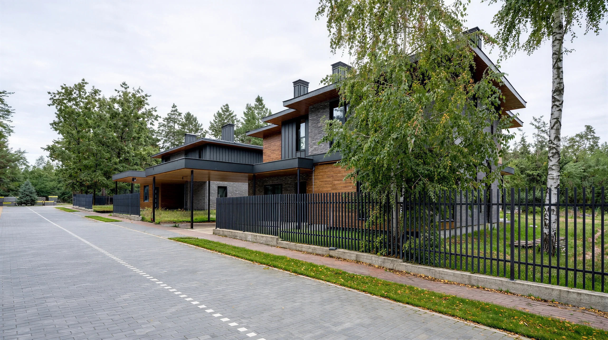 Уличный ракурс двухэтажного дома 292 м² с плоской крышей, черным забором и длинным навесом