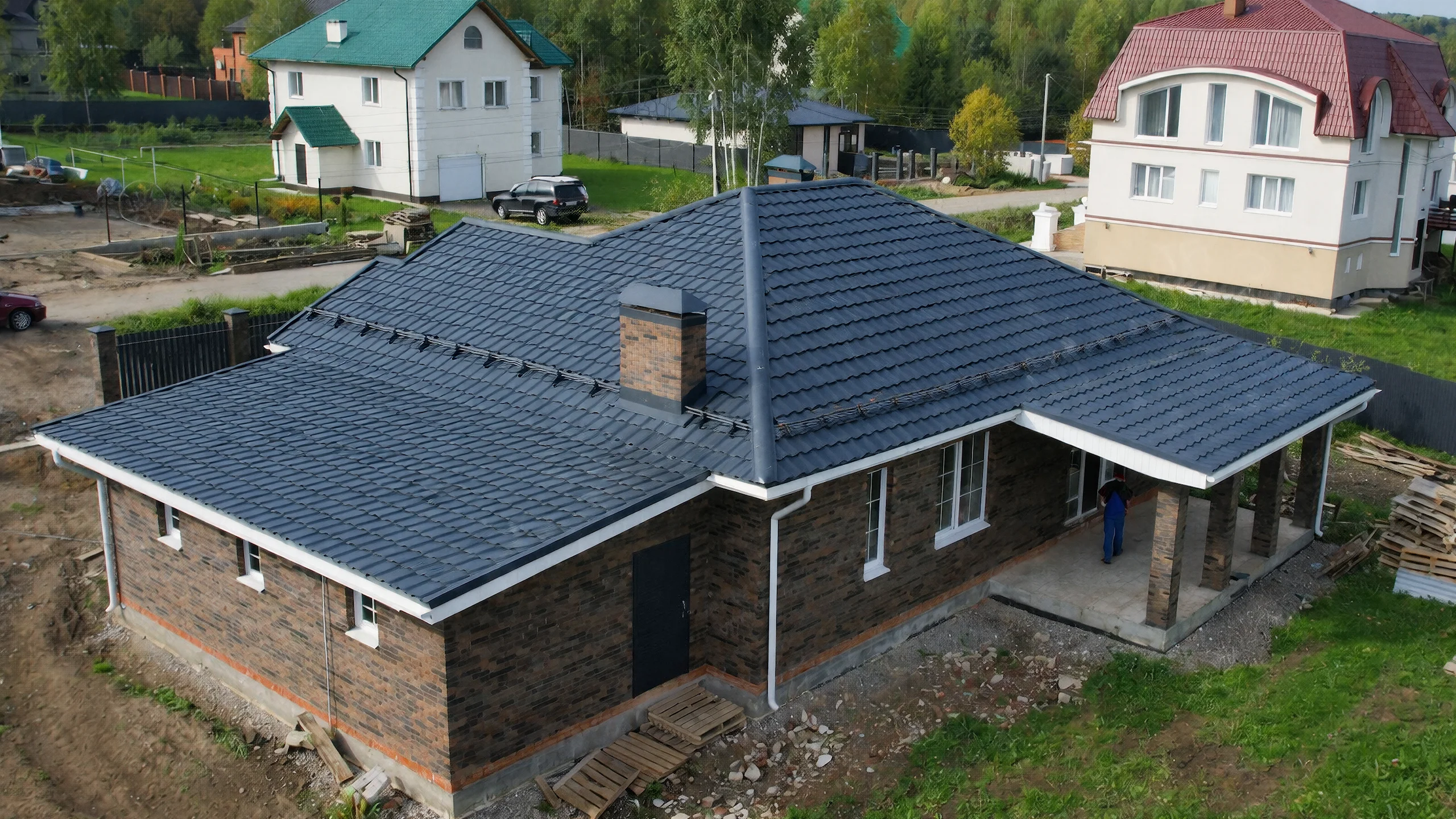 Дворовый фасад одноэтажного дома 168 м² с темной кровлей, кирпичом и крытой зоной у входа