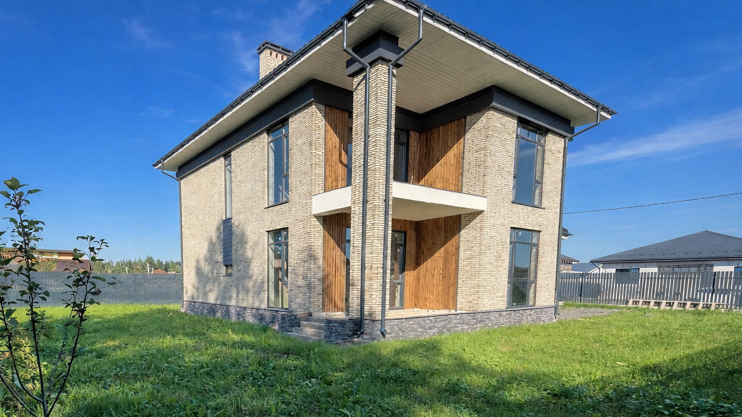 Угловой ракурс двухэтажного дома 239 м² с темной кровлей, светлым кирпичом и деревянным входным блоком