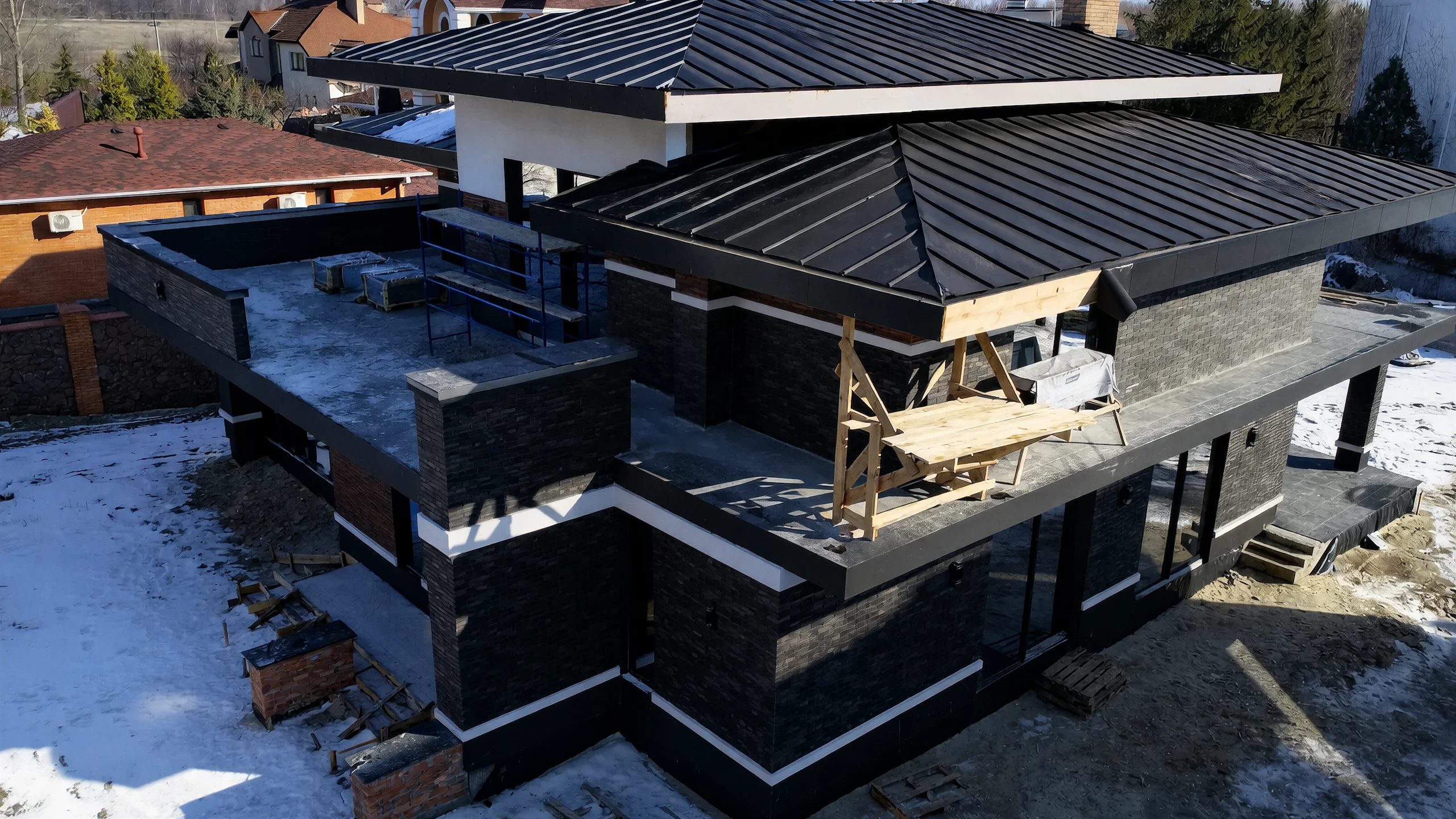 Аэрофото двухэтажного дома 524 м² с большой темной кровлей, гаражом, террасой и каменными фасадами