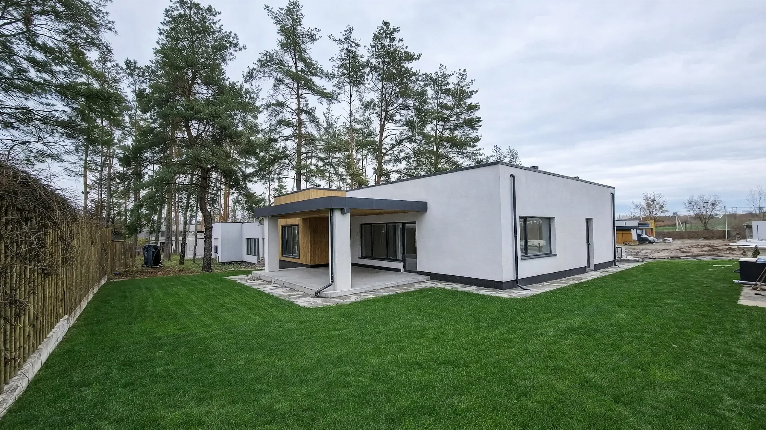 Дворовый ракурс одноэтажного дома 159 м² с плоской кровлей, белыми стенами, деревянным акцентом и террасой